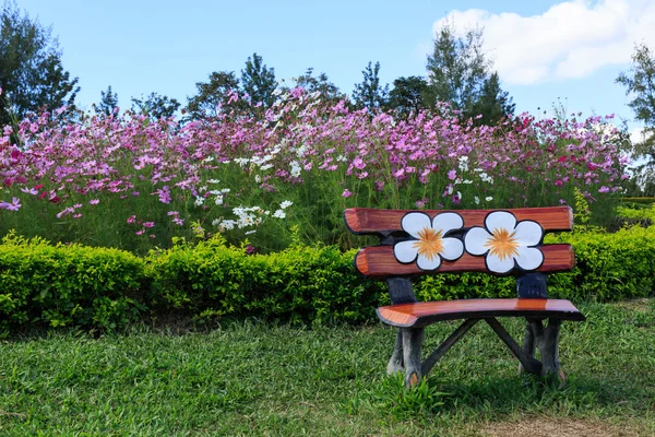 Cement Bench beside Cosmos flowers background.