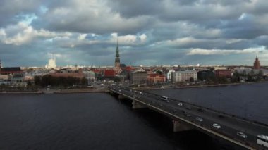 Riga 'daki Daugava nehrinin üzerinden eski kasabaya doğru uçuyor. Köprüde trafik vardı. Şehre girip çıkıyordu. Aerial Riga videosu, Letonya 'nın başkenti. 