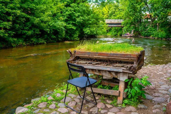 Abandoned gran piano covered with grass, rundown piano by a river bank Vilnia river in Uzupis artists quarter in Vilnius