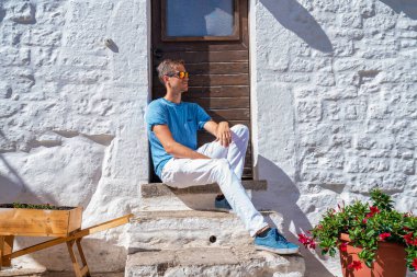İtalya 'nın Puglia bölgesindeki Bari eyaletinin Alberobello kentindeki trulli evlerin yanında oturan genç adam. Güzel İtalya, Bari bölgesi.