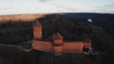 Turaida Kalesi 'nin altın saatinde güzel bir hava manzarası var. Sigulda, Letonya 'da gün batımı. Turistik bir yer. Tepenin üstündeki ortaçağ şatosunun havadan görünüşü. 