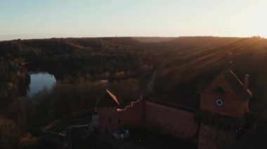 Turaida Kalesi 'nin altın saatinde güzel bir hava manzarası var. Sigulda, Letonya 'da gün batımı. Turistik bir yer. Tepenin üstündeki ortaçağ şatosunun havadan görünüşü. 