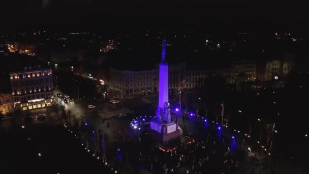 ラトビアのリガ 2020年11月18日 スタロ リガのイベント中にラトビアのリガで夜の自由の記念碑 ミルダ 異なる色で照らされた街の上に3つ星を保持する自由の女神 — ストック動画
