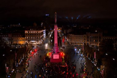 Riga, Letonya - 18 Kasım 2020: Riga, Letonya 'da Staro Riga etkinliği sırasında gece özgürlük abidesi. Milda - Özgürlük heykeli şehrin üzerinde üç yıldız tutuyor farklı renklerde aydınlatılmış.