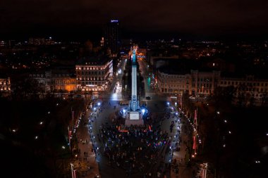 Riga, Letonya - 18 Kasım 2020: Riga, Letonya 'da Staro Riga etkinliği sırasında gece özgürlük abidesi. Milda - Özgürlük heykeli şehrin üzerinde üç yıldız tutuyor farklı renklerde aydınlatılmış.