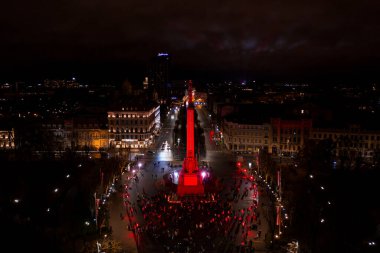 Riga, Letonya - 18 Kasım 2020: Riga, Letonya 'da Staro Riga etkinliği sırasında gece özgürlük abidesi. Milda - Özgürlük heykeli şehrin üzerinde üç yıldız tutuyor farklı renklerde aydınlatılmış.