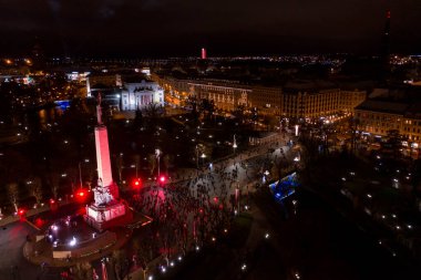 Riga, Letonya - 18 Kasım 2020: Riga, Letonya 'da Staro Riga etkinliği sırasında gece özgürlük abidesi. Milda - Özgürlük heykeli şehrin üzerinde üç yıldız tutuyor farklı renklerde aydınlatılmış.