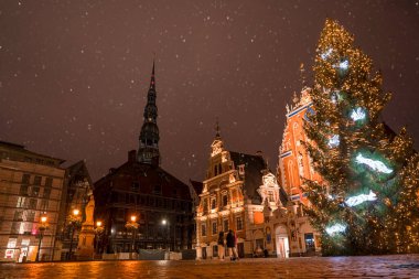 Letonya, Riga 'daki Kubbe Meydanı' nda bulunan Noel ağacı. Güzel bir gece gökyüzü ve Riga 'nın eski kasabasında havai fişekler. Noel Baba Noel ağacının yanında çocukları bekliyor..
