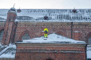Riga, Letonya. 10 Ocak 2021. Riga, Letonya 'daki St. Peters katedralinin çatısından kar temizleyen işçiler.