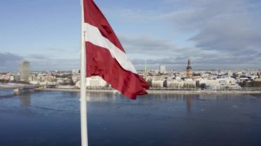 Riga şehrinin Panorama 'sı. Önünde büyük bir Letonya bayrağı var. Güneşli bir kış gününde. Arka planda büyülü eski kasaba Riga. Letonya bayrağı.