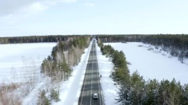 Kış ormanı boyunca yol karla kaplı. Hava aracı görünümü.