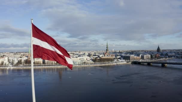 在美丽的阳光明媚的冬日里 里加市的全景 有着巨大的拉脱维亚国旗的前景 背景是奇幻的里加古城 拉脱维亚国旗 — 图库视频影像