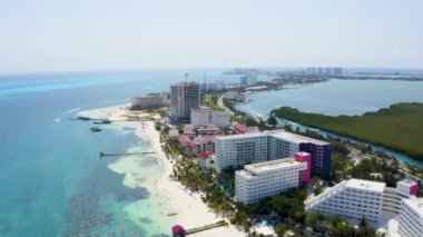 Meksika, Cancun 'un havadan görünüşü lüks tatil beldeleri ve mavi turkuaz plajları gösteriyor. İnsanlar sahilde parasailing, yüzme ve bronzlaşma yapıyor. Cancun 'daki harika Karayip plajının arka planı