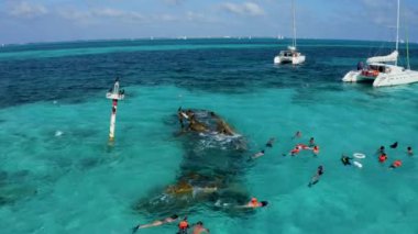 Snorkelling around the ship wrecked near Bahamas in the Caribbean sea. Beautiful turquoise water with people swimming with fishes.