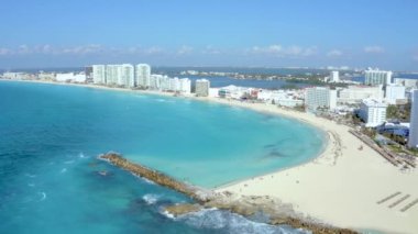 Meksika, Cancun 'un havadan görünüşü lüks tatil beldeleri ve mavi turkuaz plajları gösteriyor. İnsanlar sahilde parasailing, yüzme ve bronzlaşma yapıyor. Cancun 'daki harika Karayip plajının arka planı