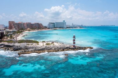 Punta Cancun Deniz Feneri 'nin hava manzarası. Deniz feneri beyaz ve kırmızı çizgilerle süslenmiş ve kayalık bir bölgede yer alıyor..