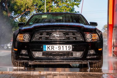 Black Ford Mustang muscle car in a car wash. clipart