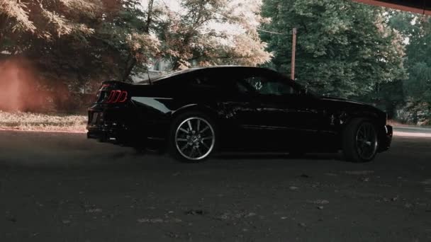 Черный Ford Mustang модель дрейфует и сжигает шины на пыльной дороге. — стоковое видео