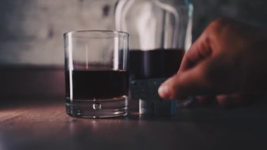 Pouring of golden whiskey, cognac or brandy from the bottle into glass