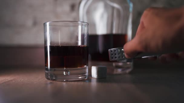 Barman nalévá zlatou whisky, koňak nebo brandy z láhve do skla na stole — Stock video