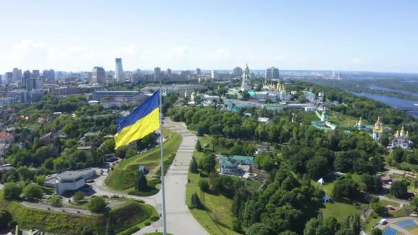 Vista aérea de la bandera ucraniana ondeando en el viento contra la ciudad de Kiev — Vídeos de Stock