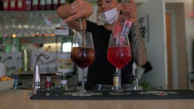 Dövmeli bir barmen Aperol Spritz kokteyline şampanya döker. 