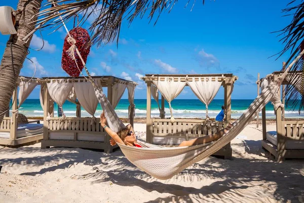 Женщина отдыхает в гамаке на прекрасном пляжном курорте с повешенными сердцами — стоковое фото