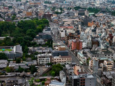 Dar sokakları, alçak binaları, geleneksel çatıları, modern yapıları ve solda yeşil bir alanı gösteren Kyoto, Japonya hava manzarası..