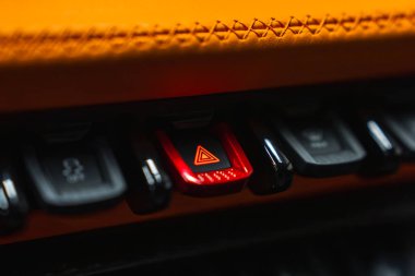 Lamborghini Urus 'un içini yakından görebiliyoruz. Işıklı kırmızı ışık düğmesi, siyah kontrol düğmeleri ve turuncu deri gösterge paneli..