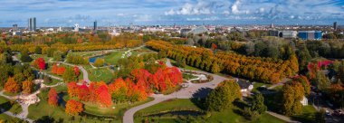 Riga, Letonya 'daki hava manzaralı canlı sonbahar yeşillikleri, dönme dolap, modern binalar ve Letonya Ulusal Kütüphanesi..