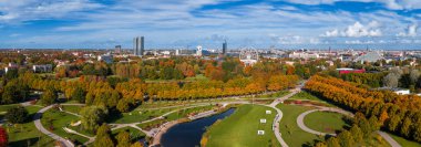 Riga, Letonya 'daki Zafer Parkı' nın havadan görünüşü, altın sonbahar yeşillikleri, dolambaçlı yolları, bir gölet ve Ulusal Kütüphane 'nin yer aldığı şehir manzarası..