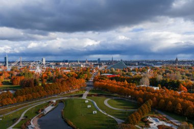 Riga, Letonya 'nın sonbahardaki gündüz görüntüsü, park yolları, göletler ve portakal ağaçları, Vansu Köprüsü, dönme dolap, Ulusal Kütüphane ve alçak bulutlar altında kilise kuleleri.