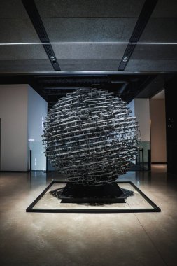 Japonya 'da lobi lobisinde metal küre gibi bir kafes, soğuk tonlarda ve spot ışıkları endüstriyel dokuyu, gölgeleri ve merkezli kompozisyonu vurgular..