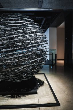 Japonya 'da loş bir modern iç mekanda bulunan metal bir kafes küresi, parlak zemine, parlak duvarlara, karanlık tavanlara ve minimal mobilyalara karmaşık gölgeler bırakıyor..