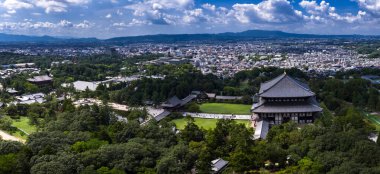 Hava görüntüsü, Japonya 'nın Nara Parkı' ndaki Todai ji Büyük Buda Salonu 'nu gösteriyor. Yürüyüşler, havuzlar, çimenler, ziyaretçiler ve şehir manzarasıyla gün ortasında uzak dağlara çıkıyor..