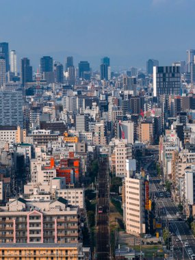 Merkez Osaka, Japonya, orta ve yüksek binalar, demiryolları ve daha yüksek kulelere giden yollar gösteriyor. Osaka Kalesi solda görünüyor. Gün ortası ışıklarını serin tonlarla temizle.