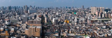 Geniş bir hava manzarası Osaka, Japonya 'yı gösteriyor, alçak ve orta bloklar, yüksek binalar, yüksek otobanlar, demiryolları ve gün ışığında Osaka Castle Park' ı gösteriyor.