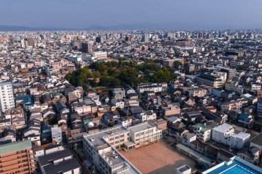 Japonya, Osaka 'nın hava manzarası, yoğun alçak katlı evler, okul bahçeleri ve öğle vakti açık ışık ve keskin kentsel detaylarla kofun höyüğü gösteriyor.