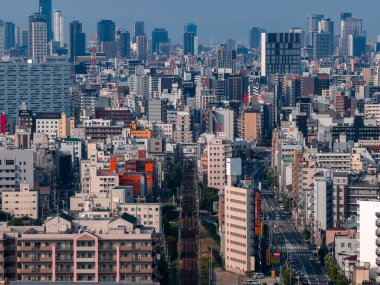 Osaka, Japonya şehir silueti yükselen daireler ve yüksek binalar gösteriyor. Osaka Kalesi, demiryolu ve tramvay hatları gün ışığında dar bloklardan geçerken solda duruyor..