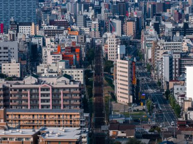 Japonya 'nın Osaka kentinin gündüz görüşü, dar caddelerden geçen raylar, orta ve yüksek bloklar ve yükseltilmiş bir noktadan görülen Japonca tabelalar.