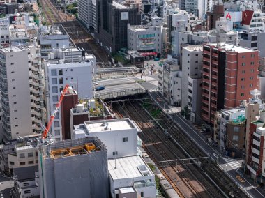 Osaka, Japonya 'daki hava manzarası paralel demiryolu hatları, bir üstgeçit ve parlak öğle vakti ışığı altında küçük ve yüksek binalar gösteriyor..