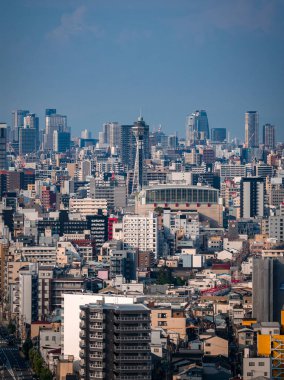 Japonya, Osaka 'nın hava manzarası Tsutenkaku Kulesi' ni orta ve yüksek binalar, demiryolları ve parlak gün ışığında hafif sisli ve yumuşak mavi tonlu beton bloklar arasında gösteriyor.