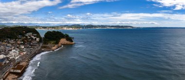 Japonya, Kamakura 'nın geniş bir hava manzarası sahil kenarındaki Enoden demiryolunu, dar evleri, küçük bir istasyonu, kayalık bir burnu, çelik mavi denizleri ve uzak tepeleri gösteriyor..