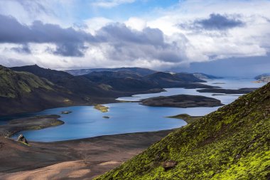 Veidivotn ya da Langisjor yakınlarındaki İzlanda 'nın Highlands bölgesindeki kobalt mavi gölleri, adacıkları ve koyu lav sahalarının gündüz açılı görüntüsü, bulutlar ve güneş ışığı karşıtlıkları yaratıyor..