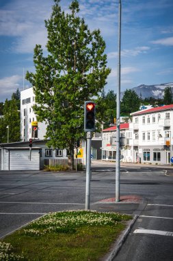 Kırmızı bir kalp yayası kırmızı çatıları, yaya geçitleri, yoncaları ve Akureyri 'deki hafif karlı dağları olan beyaz ahşap evlerin yakınlarındaki düzenli bir İzlanda köşesinde parlıyor..