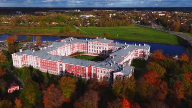 Hava aracı taraması Jelgava, Letonya 'daki Jelgava Sarayı' nı gösteriyor. U şeklinde bir yerleşim, merkez avlu, Lielupe nehri, sonbahar rengi, alçak açı ışığı ve geniş kompozisyon..