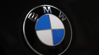 Sıkı bir makro baskı, parlak siyah bir BMW yuvarlak rozet ortaya çıkarıyor. Hafif açı değişiklikleri, yüksek kontrastlı ışık ve sığ alan derinliği vurgulu metalik bitiş.