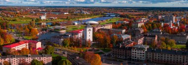 Sonbaharda Letonya, Jelgava 'nın hava manzarası. Kutsal Üçlemeci Kilisesi kulesi kıvrımlı yaya köprülerinin ve Lielupe Nehri kıyısındaki bir kubbe çatı konser salonunun yanında yükseliyor..