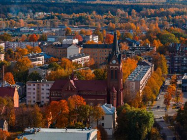 Letonya 'nın Jelgava kentinin havadan görünüşü, kırmızı tuğlalı bir Neo Gotik kilise kulesi, meskun sokaklar, midrise blokları ve öğleden sonra ormanlar aydınlık..