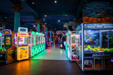 Neon atari makineleri California 'daki Santa Cruz Sahili Boardwalk' ta cilalı bir koridor hizasında. Turna oyunları ve madeni para satıcıları loş ışıkta parlıyor..